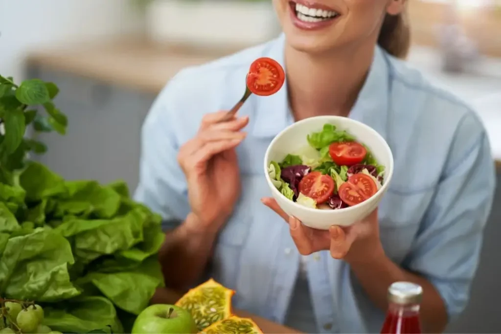 Woman enjoying fresh salad in kitchen.
